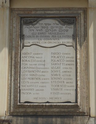 Ghetto vecchio, lapide commemorativa Lapide sorretta da un'ampia cornice sagomata a listelli degradanti. Gli angoli superiori sono decorati da motivi floreali; sotto, una lastra di marmo di Pietra Santa riporta le formule dedicatorie ebraiche. A seguire, dedica commemorativa in italiano con i nomi degli ebrei caduti durante il Primo Conflitto Mondiale.