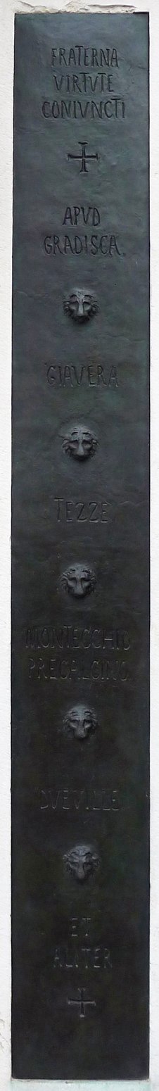 Lastra bronzea rettangolare, che riporta iscrizioni intervallate da cinque protomi leonine.
